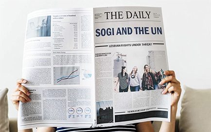 Woman reading newspaper with headlines Sogi and the UN